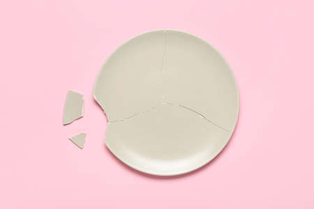 Broken ceramic plate on pink backgroundの写真素材