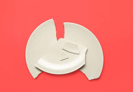 Broken ceramic plate on red backgroundの写真素材