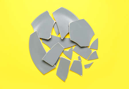 Broken ceramic plate on yellow backgroundの写真素材