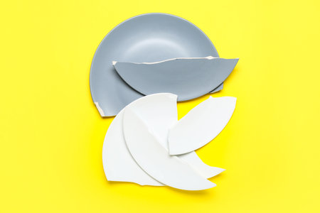 Broken ceramic plates on yellow backgroundの写真素材