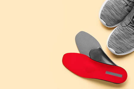 Pair of orthopedic insoles and shoes on color backgroundの写真素材