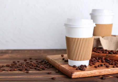 Takeaway paper cups and coffee beans on tableの写真素材