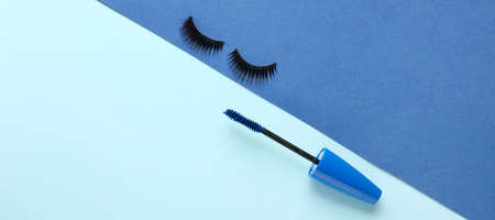 Black mascara and fake eyelashes on blue background with space for textの写真素材
