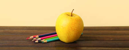 Apple with pencils on table against yellow backgroundの写真素材