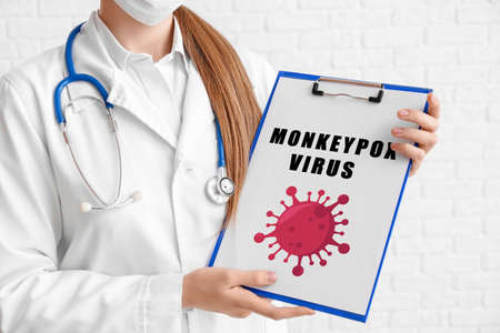 Female doctor holding clipboard with text MONKEYPOX VIRUS on white background
