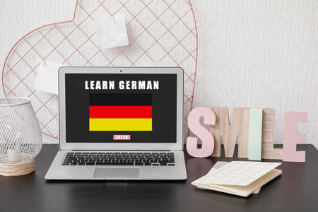 Modern laptop with text LEARN GERMAN on screen at workplace