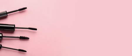 Black mascara on pink background with space for textの写真素材