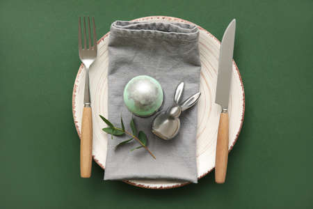 Stylish table setting for Easter celebration on green background