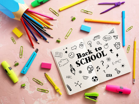 Notebook with text BACK TO SCHOOL and set of bright stationery on pink backgroundの写真素材