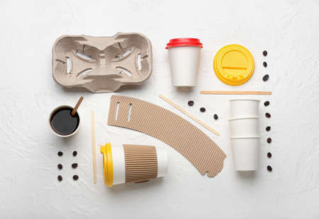 Takeaway paper cups, coffee beans, holder and spoons on white backgroundの写真素材