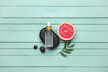 Composition with half of grapefruit and bottle of essential oil on color wooden backgroundの写真素材