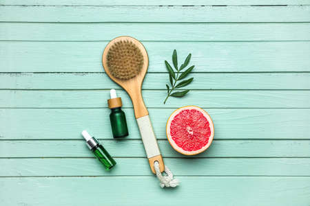 Composition with half of grapefruit, brush and bottles of essential oil on color wooden backgroundの写真素材