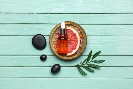 Composition with slice of grapefruit and bottle of essential oil on color wooden backgroundの写真素材