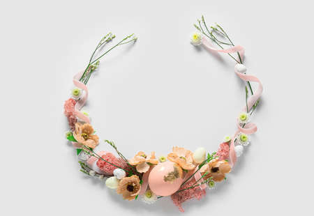 Beautiful wreath with Easter eggs and flowers on light backgroundの写真素材