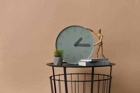 Table with modern clock, books and mannequin near color wall in roomの写真素材