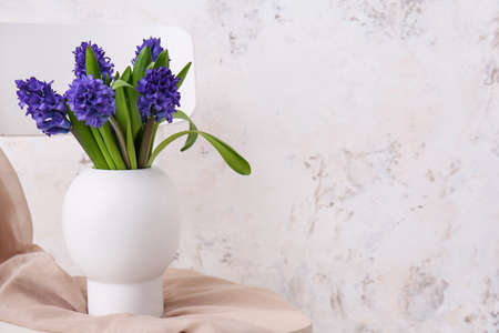 Vase with beautiful flowers on chair near light wallの写真素材