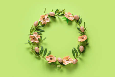 Beautiful wreath with Easter eggs and flowers on green backgroundの写真素材