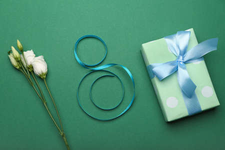 Figure 8 made of ribbon, gift box and flowers for International Women's Day celebration on green backgroundの写真素材