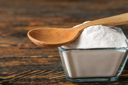 Bowl of baking soda and spoon on wooden backgroundの写真素材