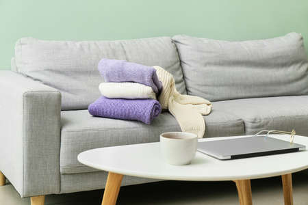 Stack of knitted sweaters on sofa in roomの写真素材