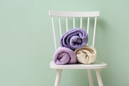 Rolled sweaters on chair near color wallの写真素材