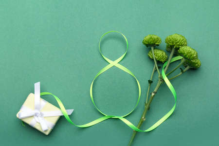 Figure 8 made of ribbon, gift box and flowers for International Women's Day celebration on green backgroundの写真素材