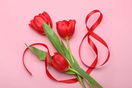 Figure 8 made of ribbon and flowers for International Women's Day celebration on pink background
