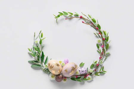 Beautiful wreath with Easter eggs and flowers on light backgroundの写真素材