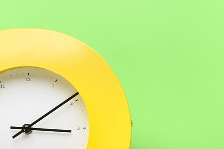 New modern clock on green background, closeup