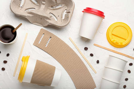Takeaway paper cups, coffee beans, holder and spoons on white backgroundの写真素材