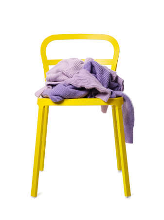 Crumpled lilac sweaters on yellow chair against white backgroundの写真素材