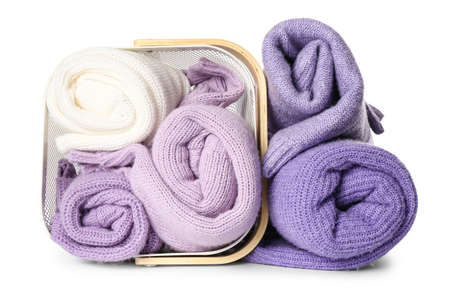 Overturned basket with rolled sweaters on white backgroundの写真素材
