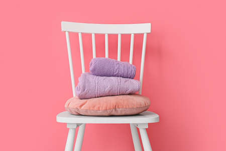 Stack of folded lilac sweaters on chair near color wallの写真素材