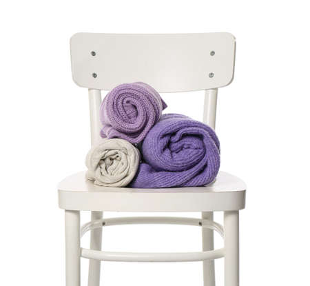 Rolled sweaters on chair against white backgroundの写真素材