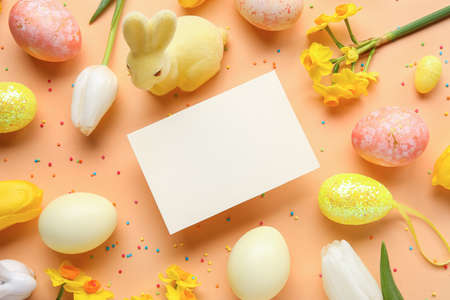 Beautiful Easter composition with blank card, eggs and flowers on color backgroundの写真素材