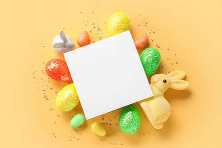 Composition with blank card, beautiful Easter eggs and decor on color background
