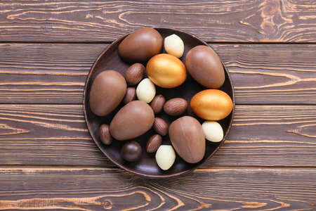 Plate with different chocolate Easter eggs on wooden backgroundの写真素材