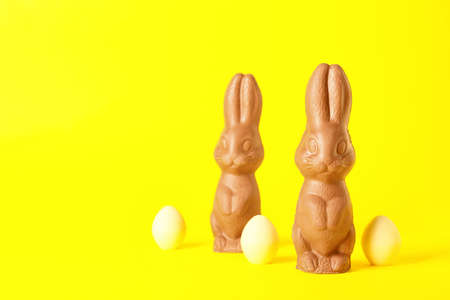 Chocolate Easter bunnies and eggs on yellow backgroundの写真素材