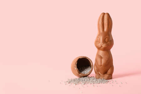 Chocolate Easter bunny and broken egg with sprinkles on pink backgroundの写真素材