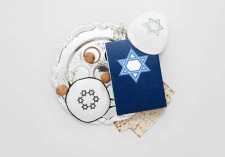 Passover Seder plate, flatbread matza, Torah and hats on light backgroundの写真素材