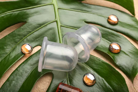 Vacuum jars for anti-cellulite massage and glass stones on palm leaf, closeup