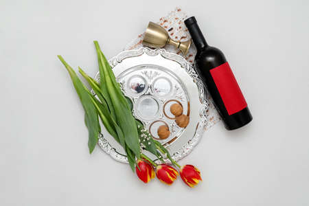 Passover Seder plate, flowers, walnuts and wine on light backgroundの写真素材