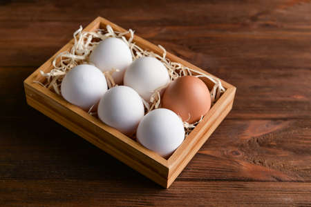 Box with fresh chicken eggs on wooden background