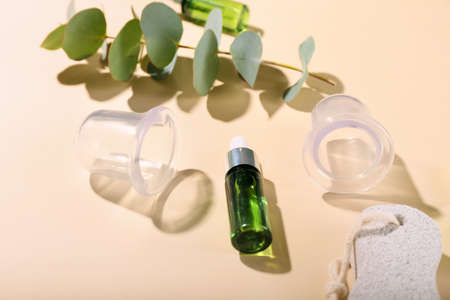 Composition with bottle of essential oil and vacuum jars for anti-cellulite massage on color backgroundの写真素材