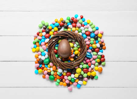 Composition with chocolate Easter egg and different candies on light wooden backgroundの写真素材