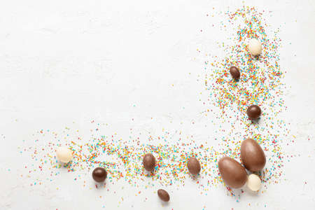 Composition with tasty chocolate Easter eggs and sprinkles on light backgroundの写真素材