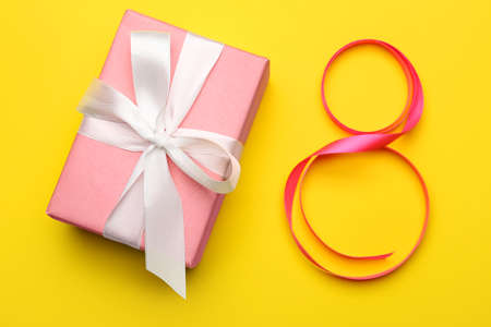 Figure 8 made of ribbon and gift for International Women's Day celebration on yellow background