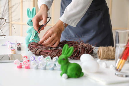 Woman making Easter wreath on table in light roomの写真素材