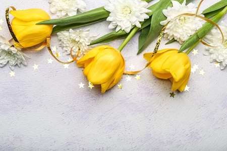 Beautiful flowers and confetti on light background, closeup. International Women's Day celebration