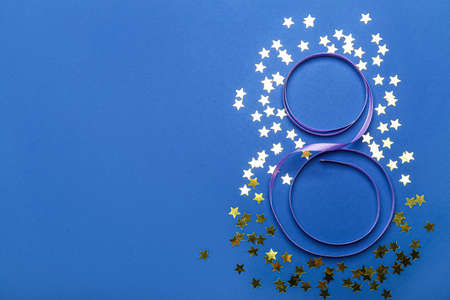 Figure 8 made of ribbon and confetti on color background, closeup. International Women's Day...